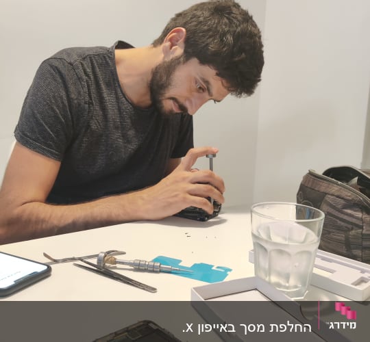 אדם מתקן אייפון עם כלים על שולחן